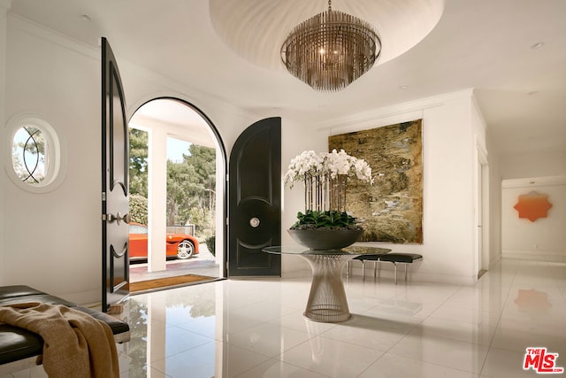 doorway to outside featuring a chandelier, light tile patterned floors, and a raised ceiling