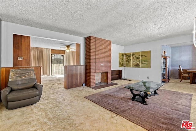 carpeted living room featuring ceiling fan, a textured ceiling, wood walls, and a fireplace