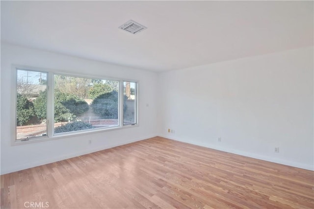 empty room with visible vents, light wood-style flooring, and baseboards