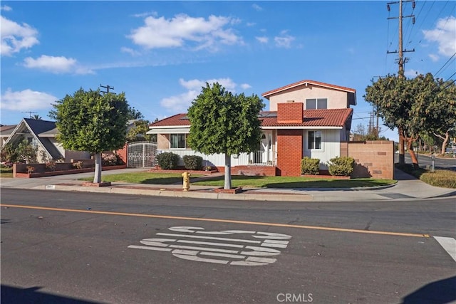 view of front of home with fence, a tiled roof, concrete driveway, a gate, and roof mounted solar panels