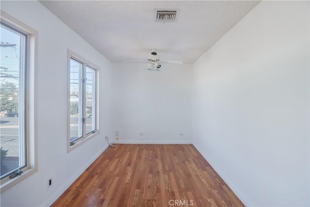 unfurnished room featuring a ceiling fan, wood finished floors, visible vents, and baseboards