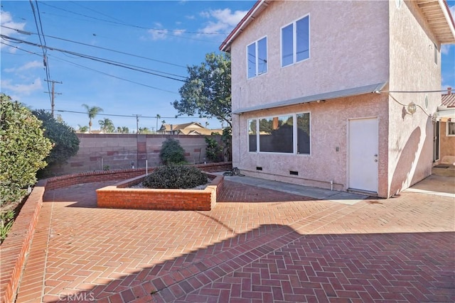 rear view of house with crawl space, fence, a patio, and stucco siding