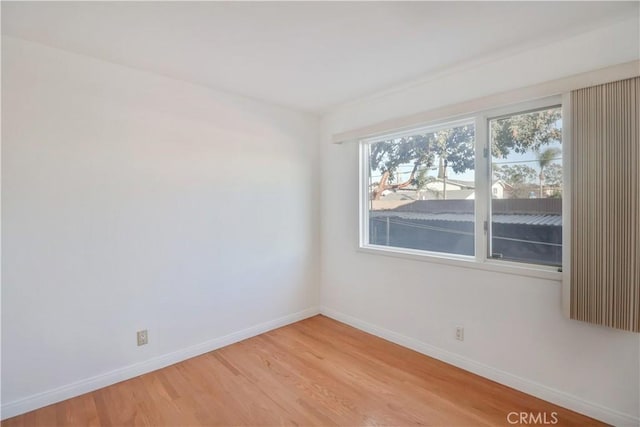 spare room with baseboards and light wood-style floors