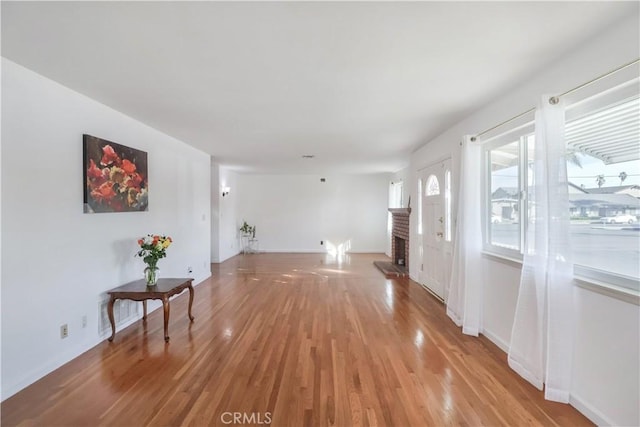 interior space featuring a fireplace, light wood-style flooring, and baseboards