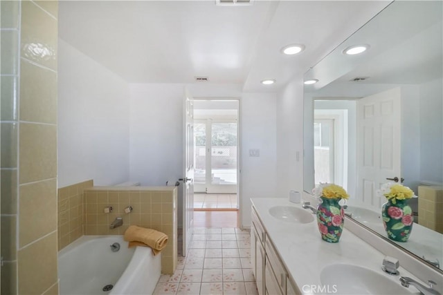 bathroom featuring double vanity, a garden tub, tile patterned flooring, and a sink