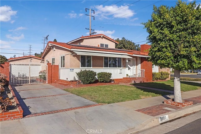 view of front of home with a tiled roof, a front lawn, a gate, and stucco siding