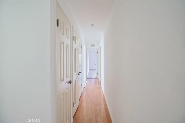 corridor with baseboards and light wood finished floors