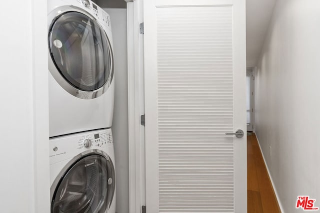 laundry area featuring hardwood / wood-style floors and stacked washing maching and dryer