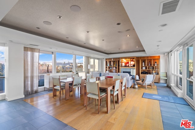 dining area with light wood-type flooring and a raised ceiling