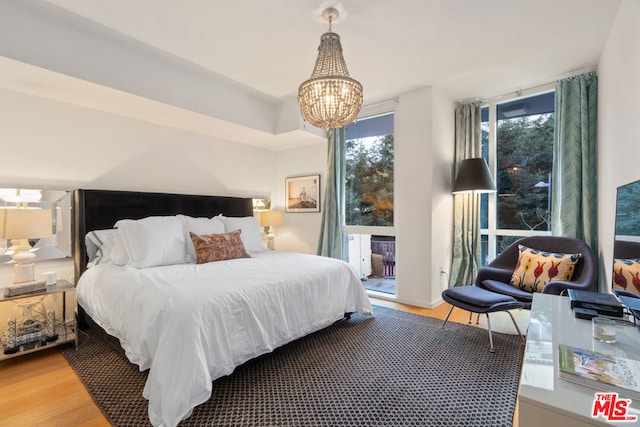 bedroom featuring an inviting chandelier and wood-type flooring