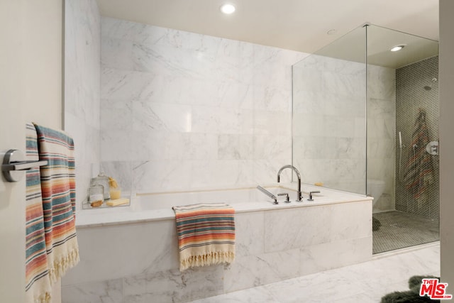 bathroom with tile walls and separate shower and tub