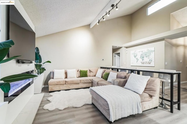 living room with rail lighting, light wood-type flooring, and a textured ceiling