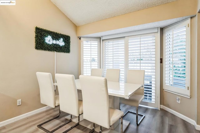 dining room with hardwood / wood-style flooring, lofted ceiling, and a textured ceiling