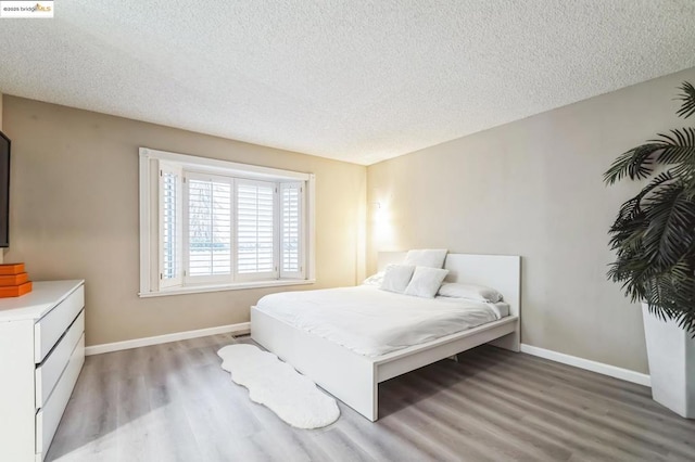 bedroom with a textured ceiling and light wood-type flooring