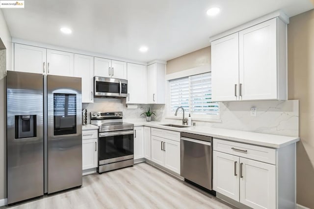 kitchen with white cabinetry, appliances with stainless steel finishes, sink, and backsplash