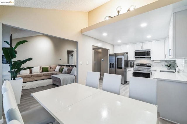 kitchen with sink, appliances with stainless steel finishes, kitchen peninsula, decorative backsplash, and white cabinets