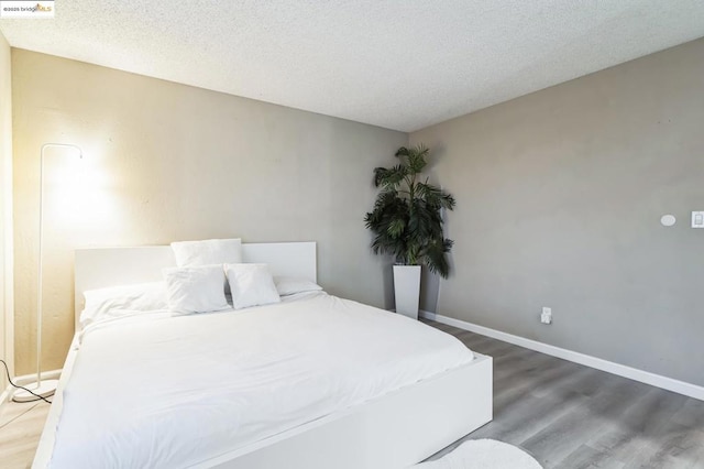 bedroom featuring a textured ceiling and dark hardwood / wood-style flooring