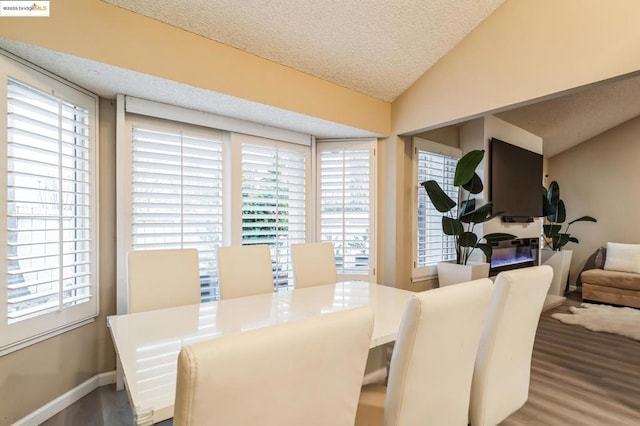 dining room featuring wood-type flooring, a textured ceiling, and vaulted ceiling