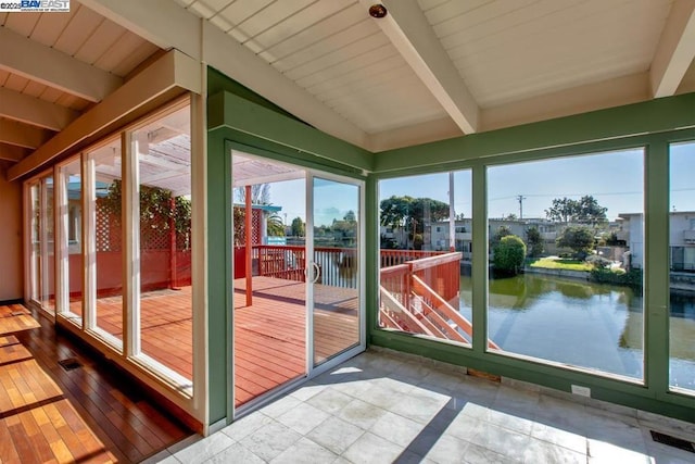 unfurnished sunroom featuring a water view and vaulted ceiling with beams