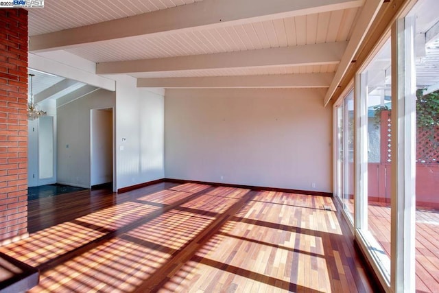 spare room with dark wood-type flooring and vaulted ceiling with beams