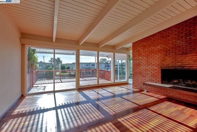 unfurnished sunroom with beamed ceiling and a fireplace