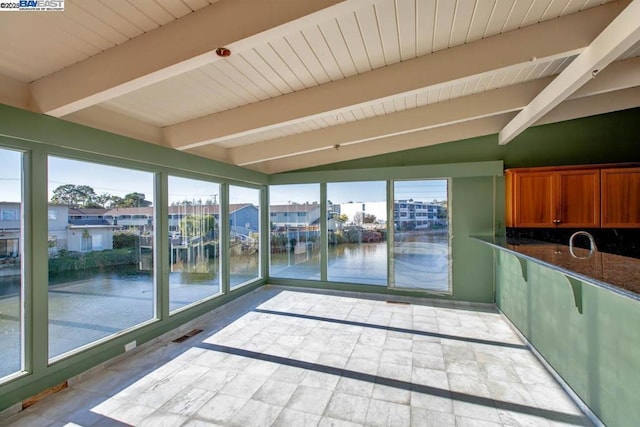 interior space with sink, a water view, and vaulted ceiling with beams