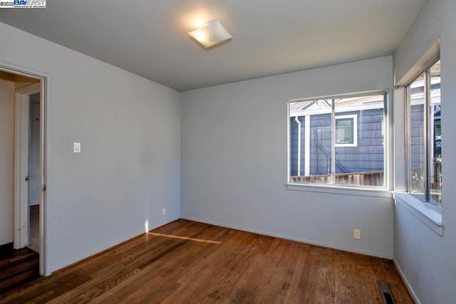 unfurnished room with dark wood-type flooring