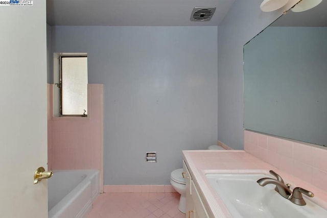 bathroom with a tub, toilet, vanity, and tile patterned flooring