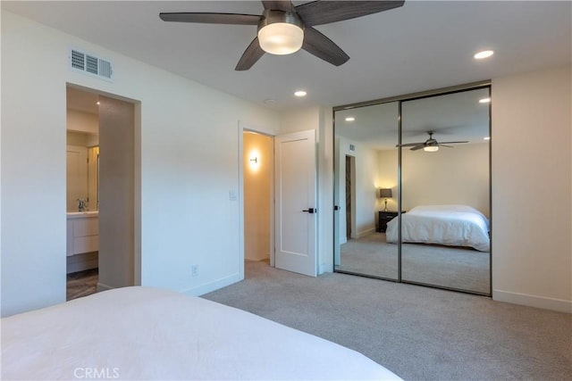 bedroom featuring ceiling fan, ensuite bath, a closet, and light carpet