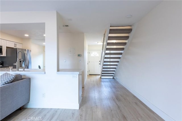 interior space with stainless steel appliances, white cabinetry, and light hardwood / wood-style floors