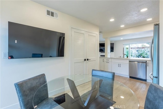 dining space featuring sink, light hardwood / wood-style floors, and a textured ceiling