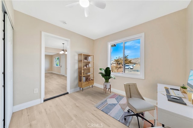 home office with light wood finished floors, a ceiling fan, and baseboards