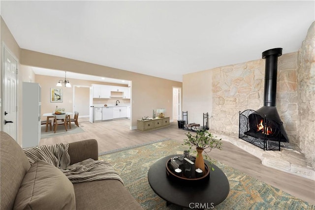 living room featuring light wood-type flooring, a wood stove, and baseboards
