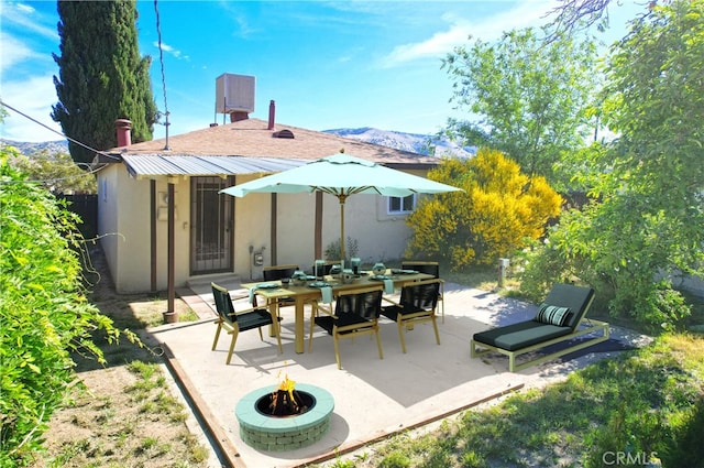 rear view of house featuring a patio area, a fire pit, stucco siding, and a mountain view