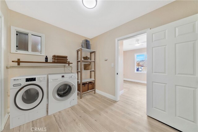 clothes washing area featuring washer and dryer, light wood finished floors, and baseboards