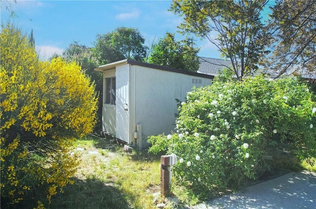 view of property exterior featuring an outbuilding, a storage unit, and stucco siding