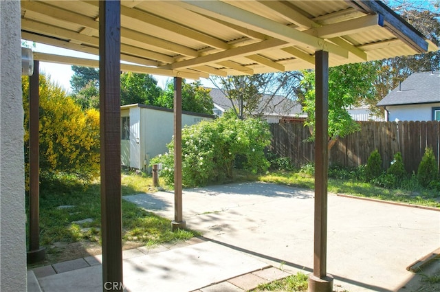 view of patio / terrace featuring fence, an outdoor structure, and a storage shed