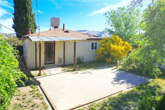 rear view of house featuring stucco siding, a patio, and a mountain view