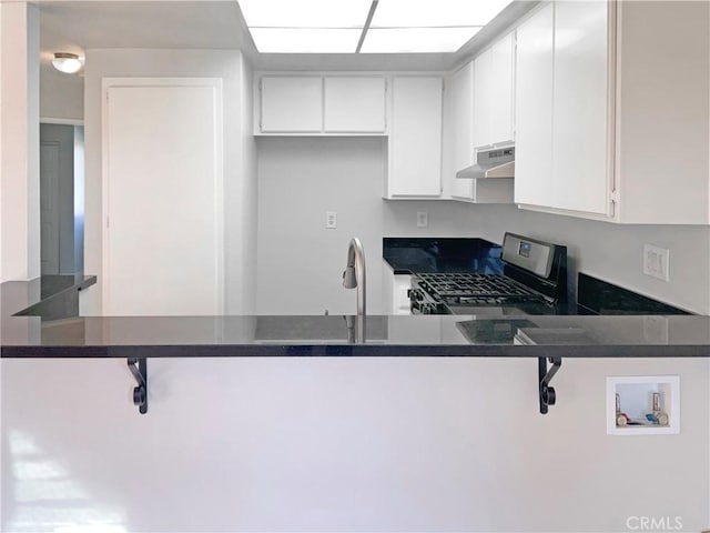 kitchen featuring kitchen peninsula, white cabinets, a breakfast bar area, and stainless steel gas range