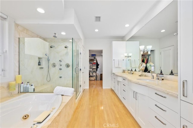 bathroom with independent shower and bath, vanity, and hardwood / wood-style floors