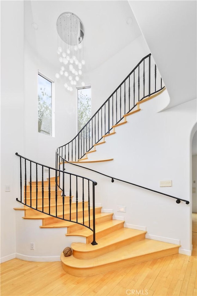 stairway with wood-type flooring and a chandelier