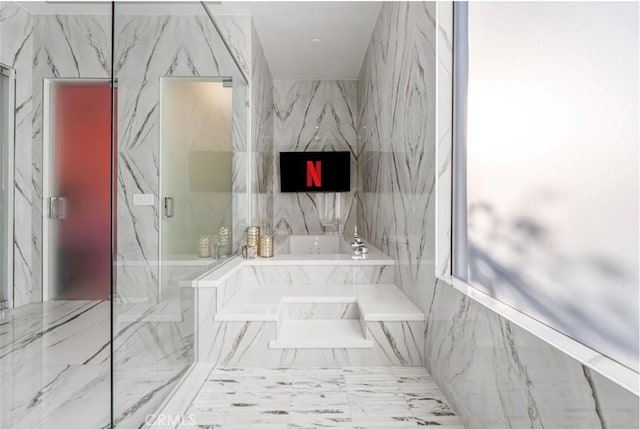 bathroom featuring a marble finish shower and a bath