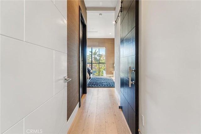 hall featuring light wood-type flooring and a barn door