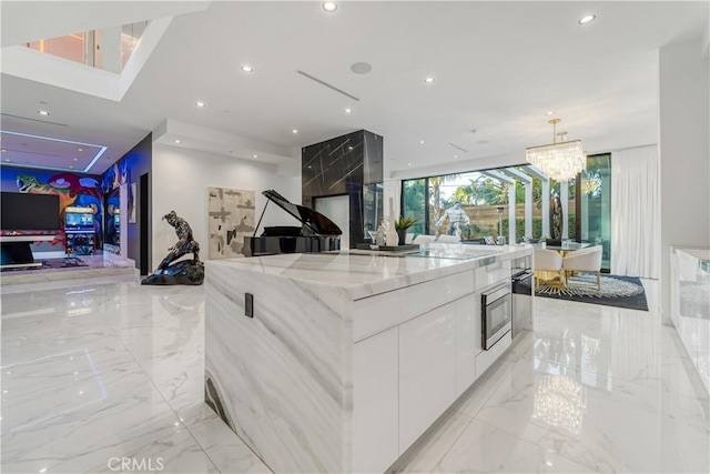 kitchen featuring light stone countertops, white cabinets, marble finish floor, modern cabinets, and open floor plan