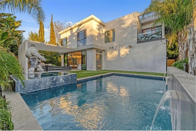 back of property with a balcony, pool water feature, a pool with hot tub, and a pergola