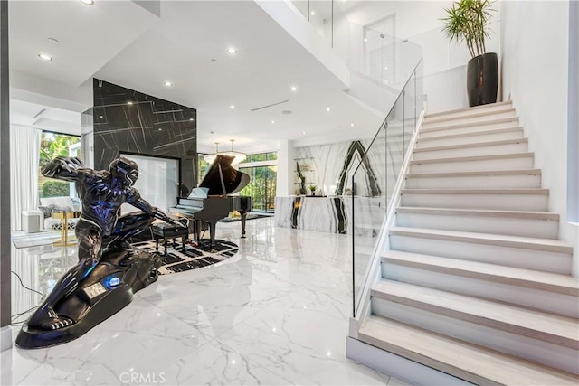 staircase featuring stone wall, recessed lighting, and marble finish floor