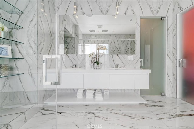 full bathroom featuring a marble finish shower and vanity