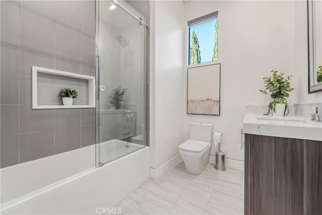 full bath with toilet, vanity, baseboards, and shower / bath combination with glass door