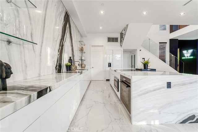 kitchen featuring light stone counters, visible vents, white cabinets, modern cabinets, and marble finish floor