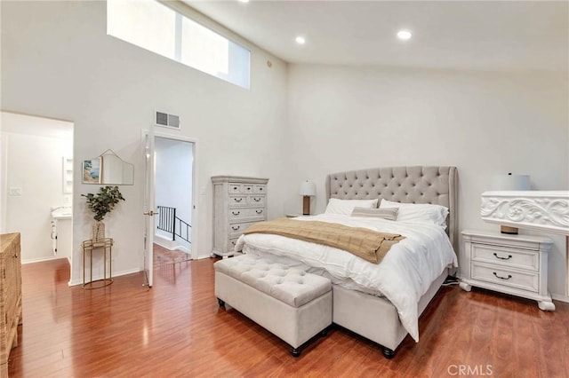 bedroom featuring hardwood / wood-style flooring and a towering ceiling